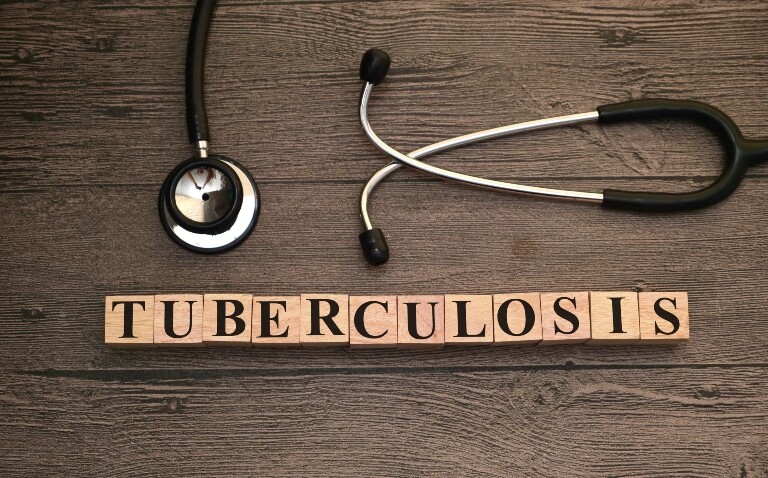 Tuberculosis written with wooden letter blocks on a wooden background with a stethoscope at the top to illustrate that action is required to tackle the condition as rates are continuing to rise in the UK