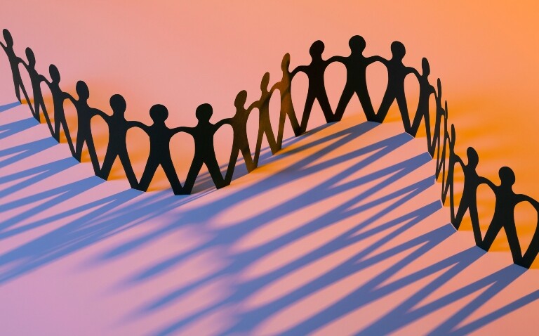 A paper chain of people shapes on a graduated orange to pink background to illustrate the finding that age at prediabetes diagnosis is linked to cancer risk