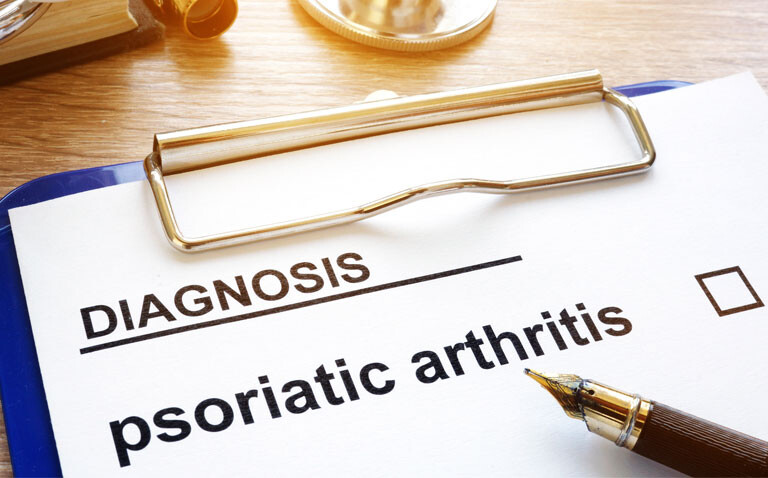 A clipboard with psoriatic arthritis listed under a heading of diagnosis with a fountain pen across the corner to illustrate diagnostic delays and reduced DMARD treatment being identified in psoriatic arthritis compared to rheumatoid arthritis