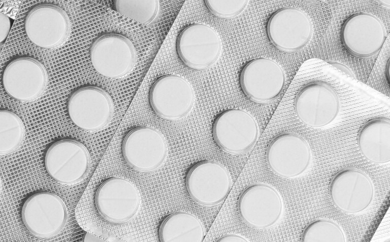 A close up of multiple silver blister packets of medication with white tablets visible through the clear blisters to illustrate research suggesting aspirin use should be discontinued in high-risk patients with chronic coronary syndrome who had prior stenting and were receiving long-term oral anticoagulation due to an increased risk in adverse and fatal outcomes