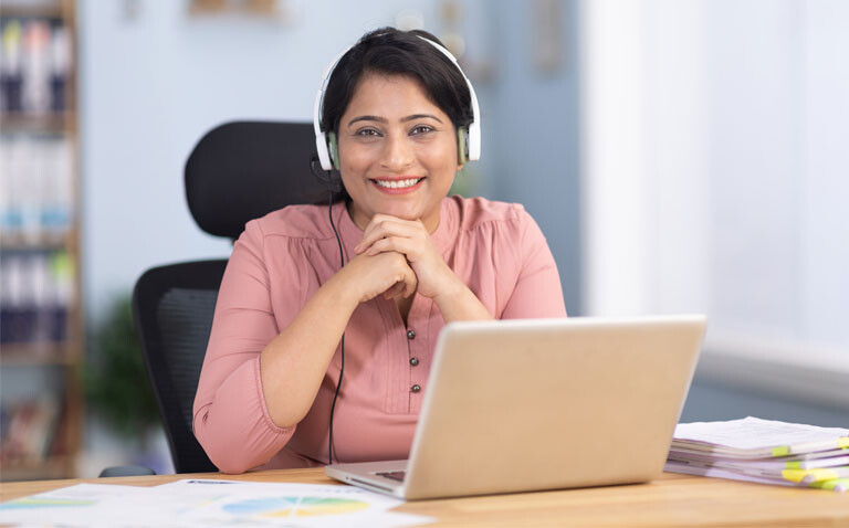 Smiling woman with headphones at a desk