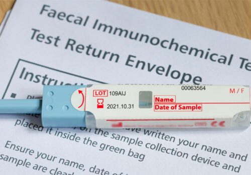 A faecal immunochemical test (FIT) sitting on top of an instruction leaflet