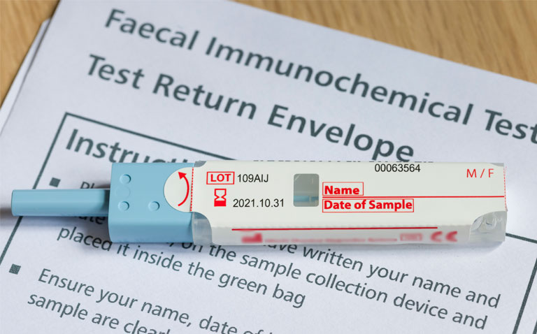 A faecal immunochemical test (FIT) sitting on top of an instruction leaflet