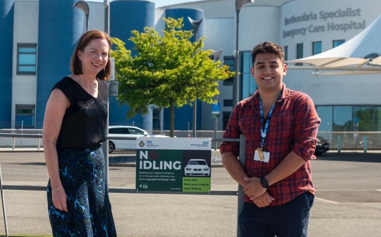 Two emergency department colleagues standing outside the Northumbria Specialist Emergency Care Hospital building in front of a No Idling sign as part of their GreenED sustainability efforts