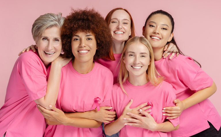 Group of five diverse women wearing pink tshirts with breast cancer ribbons