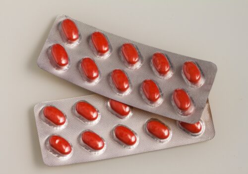 Two blister packs of opaque red tablets to illustrate isotretinoin and new prescribing requirements from the MHRA