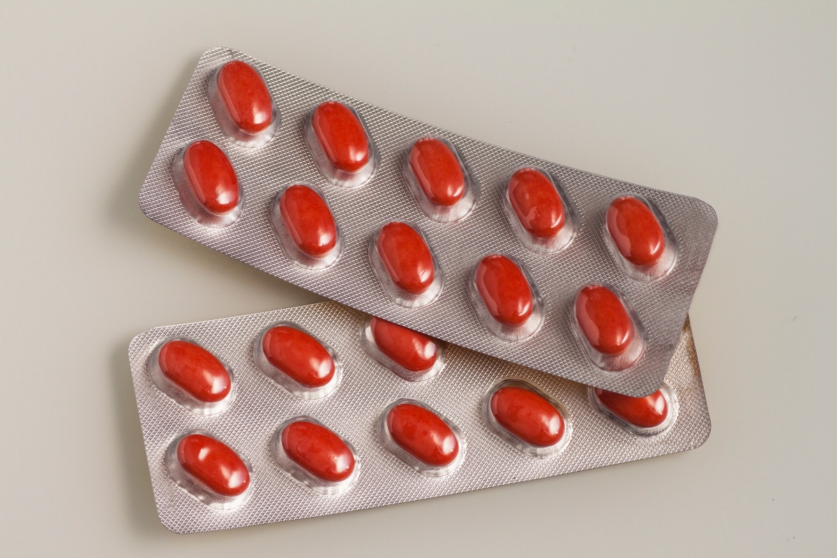 Two blister packs of opaque red tablets to illustrate isotretinoin and new prescribing requirements from the MHRA