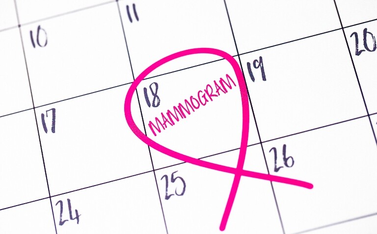 A calendar page with mammogram written in pink in the box for the 18th with a pink bread cancer ribbon drawn around it