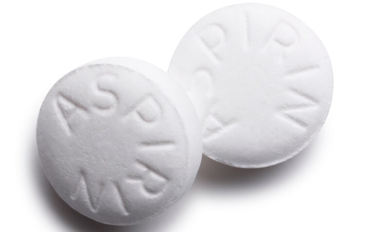 Close-up image of two white aspirin tablets with the word 