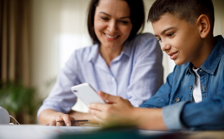 A mother and son sat looking at a smartphone to illustrate the finding that smart inhaler feedback in uncontrolled asthma does not offer benefit