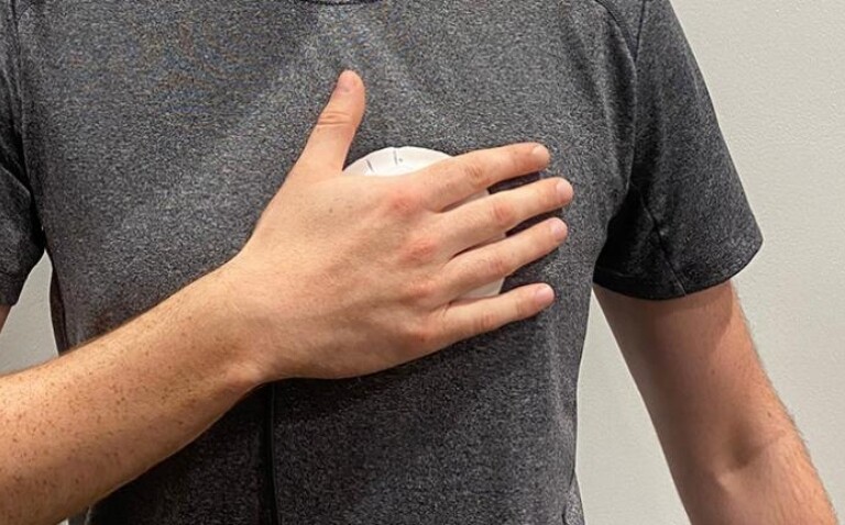 Person demonstrating use of a handheld device for valvular heart disease screening