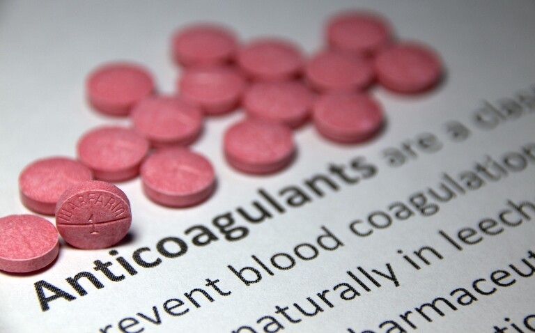 A close up of a portion of a dictionary definition of anticoagulation with warfarin tablets scattered at the top to illustrate the risks of stopping anticoagulation in older people with atrial fibrillation