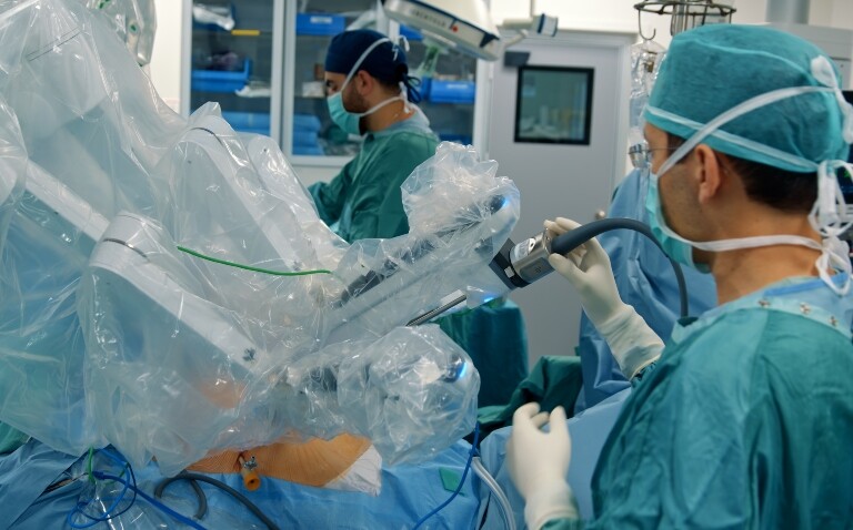 Team of healthcare professionals performing laparoscopic surgery with a medical robot to illustrate radical plans for robotic surgery in the NHS to reduce waiting lists