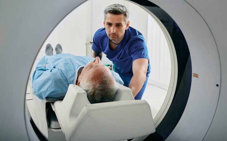 A senior man going into an MRI scanner with a healthcare professional on hand to help to illustrate the real-world diagnostic value of 4D flow CMR in aortic stenosis
