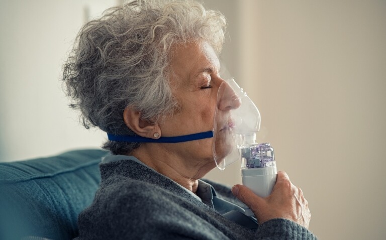 Profile view of a senior woman using a nebuliser at home illustrating that smoking may not explain the disparity in COPD rates between the sexes