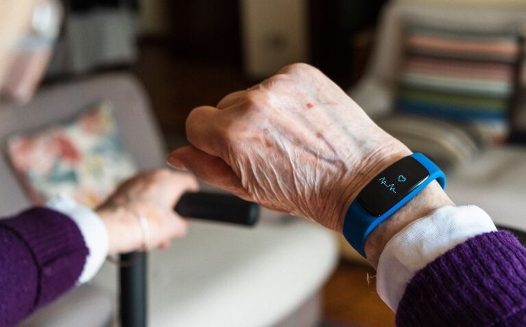 An old person at home looking at a smartwatch to track heart rate
