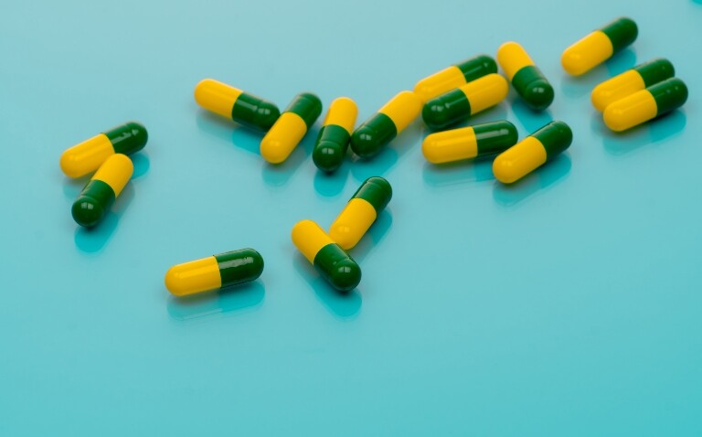 Green-yellow capsules spread on blue background to illustrate the finding that tramadol harms outweigh limited benefits for chronic pain
