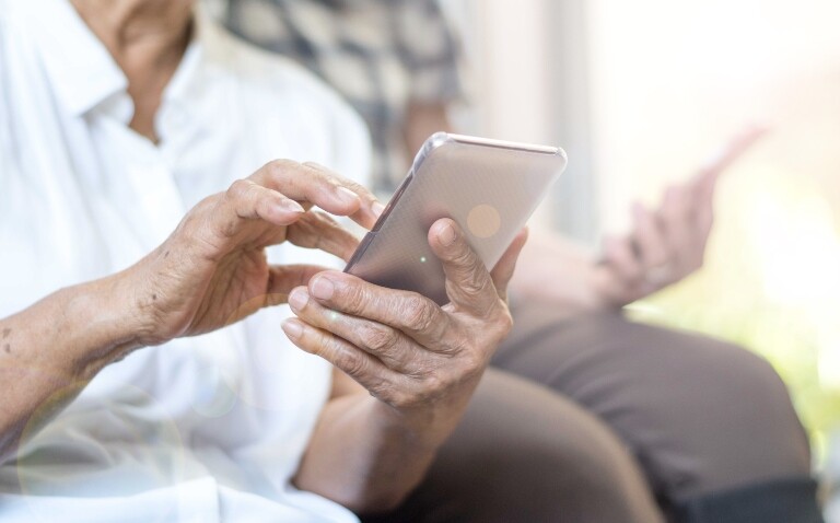 C close up of two elderly people looking at smartphones to illustrate clinical trial transformation through NHS App integration