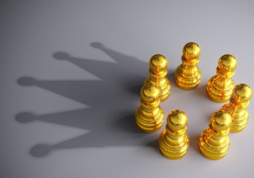 Seven gold coloured chess pawns in a circle making a shadow of a crown on a grey background to represent gold-standard MDT support in breast cancer care with support from Breast Cancer Now