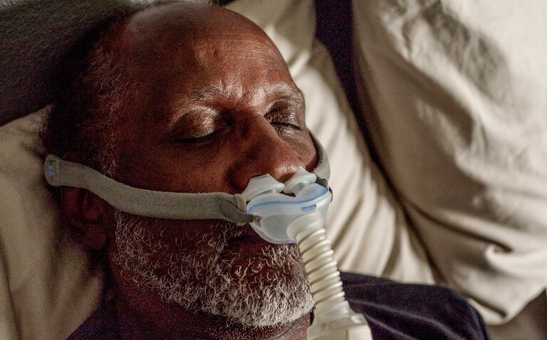 A close-up of an older gentleman asleep in bed wearing a CPAP machine to illustrate a new ERS consensus statement on the use of advanced telemedicine in obstructive sleep apnoea