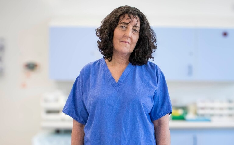 A headshot of Professor Felicity Meyer standing in a hospital in blue scrubs to illustrate women in surgery