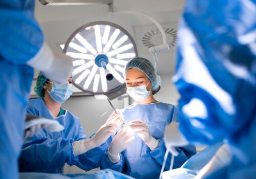 A team of professional doctors performing operation in a bright and modern operating theatre to illustrate the finding that broad-spectrum antibiotics are superior in preventing colorectal surgical site infections