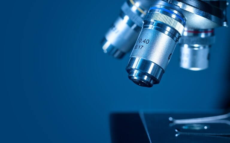 Closeup of a modern microscope on a dark blue background