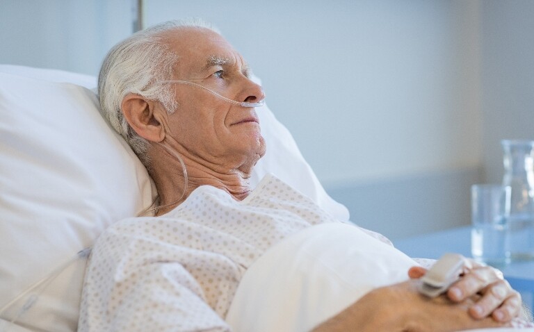 Old man laying in a hospital bed to illustrate that geriatric syndromes