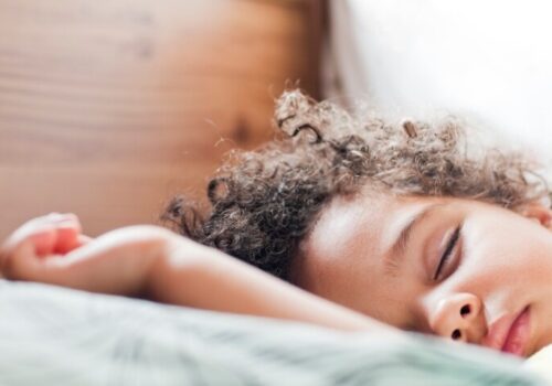 A child asleep in bed to illustrate that intranasal saline confers benefits over steroids in childhood obstructive sleep-disordered breathing