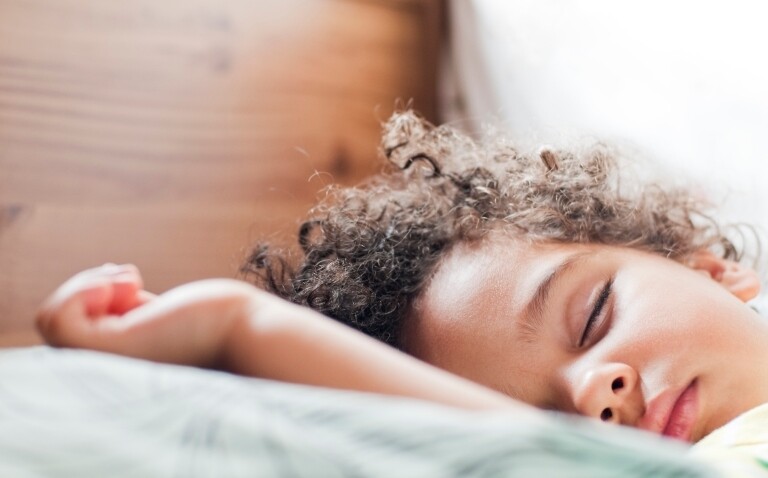 A child asleep in bed to illustrate that intranasal saline confers benefits over steroids in childhood obstructive sleep-disordered breathing