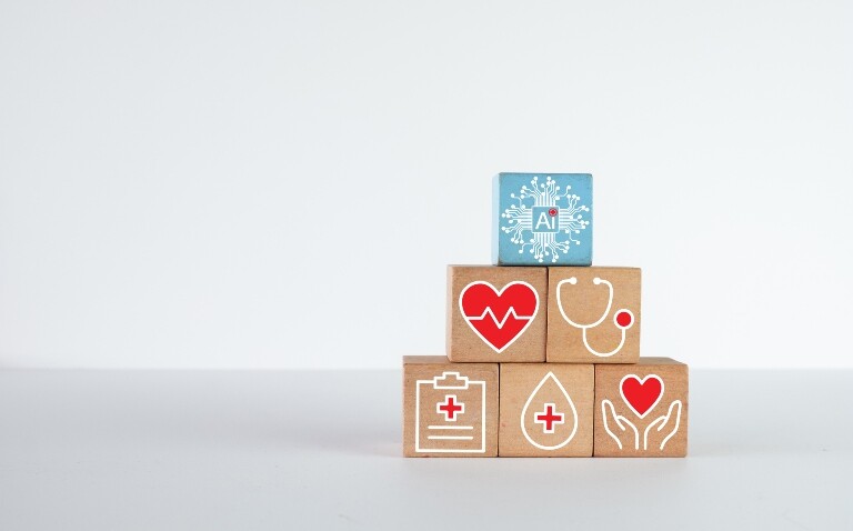 A blue block with an AI icon on top of a pyramid of wooden blocks containing medical symbols relating to heart health to illustrate machine learning-assisted mapping of VT ablation targets