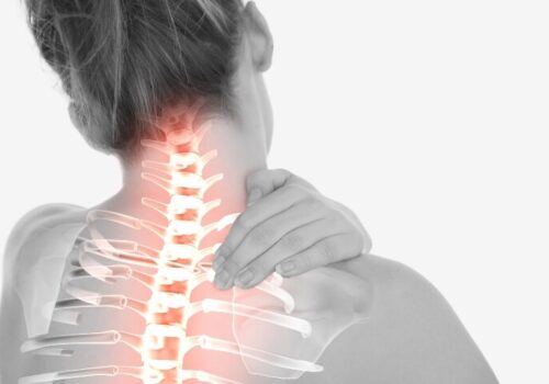 Grayscale image of a woman seen from behind holding her neck
