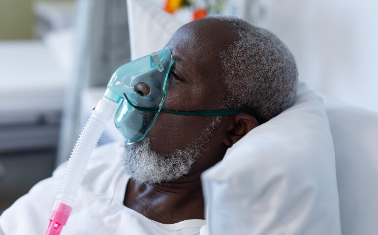An old man laying in a hospital bed with an oxygen mask on to illustrate managing complex ventilatory failure beyond OSA