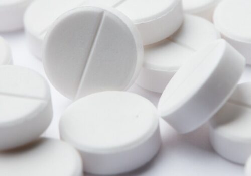 A close up on a collection of white pills to illustrate low-dose aspirin use in older adults being linked to higher cancer mortality with no reduction in 10-year incidence