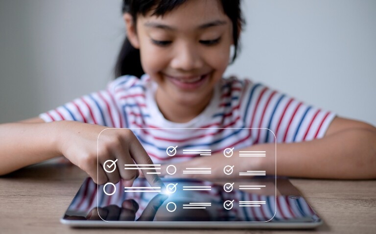 A young girl sitting at a desk with a tablet computer with a questionnaire tick box overlayed to illustrate a new P-POM for determining HRQOL in paediatric specialist care