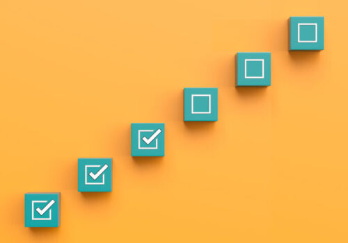 Six green blocks in a diagonal line on an orange background with the bottom three having white ticks in the centres to illustrate revised response criteria sharpening focus on underlying inflammation in RA