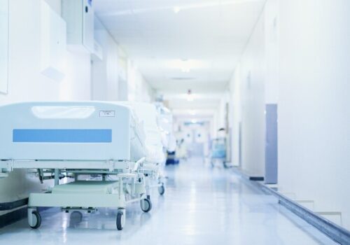 A view down a hospital corridor with hospital beds lining the walls to illustrate a spotlight on corridor care from HSSIB and RCEM