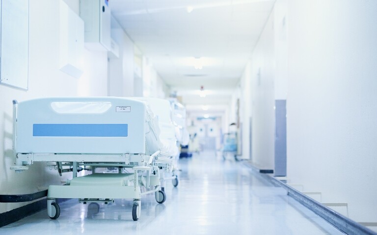 A view down a hospital corridor with hospital beds lining the walls to illustrate a spotlight on corridor care from HSSIB and RCEM