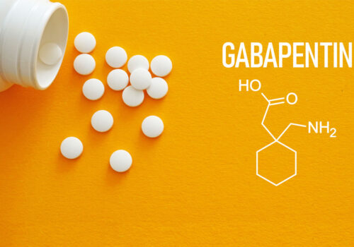 White tablets spilling from a pill bottle onto a bright yellow background beside the word ‘Gabapentin’ and the drug’s chemical structure diagram