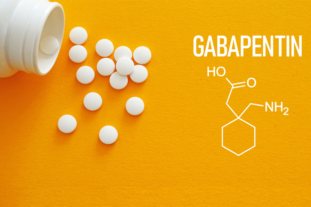 White tablets spilling from a pill bottle onto a bright yellow background beside the word ‘Gabapentin’ and the drug’s chemical structure diagram