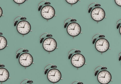 Pattern flat lay composition of black antique alarm clock on green background to illustrate the finding that late morning cardiac surgery is linked to higher cardiovascular mortality