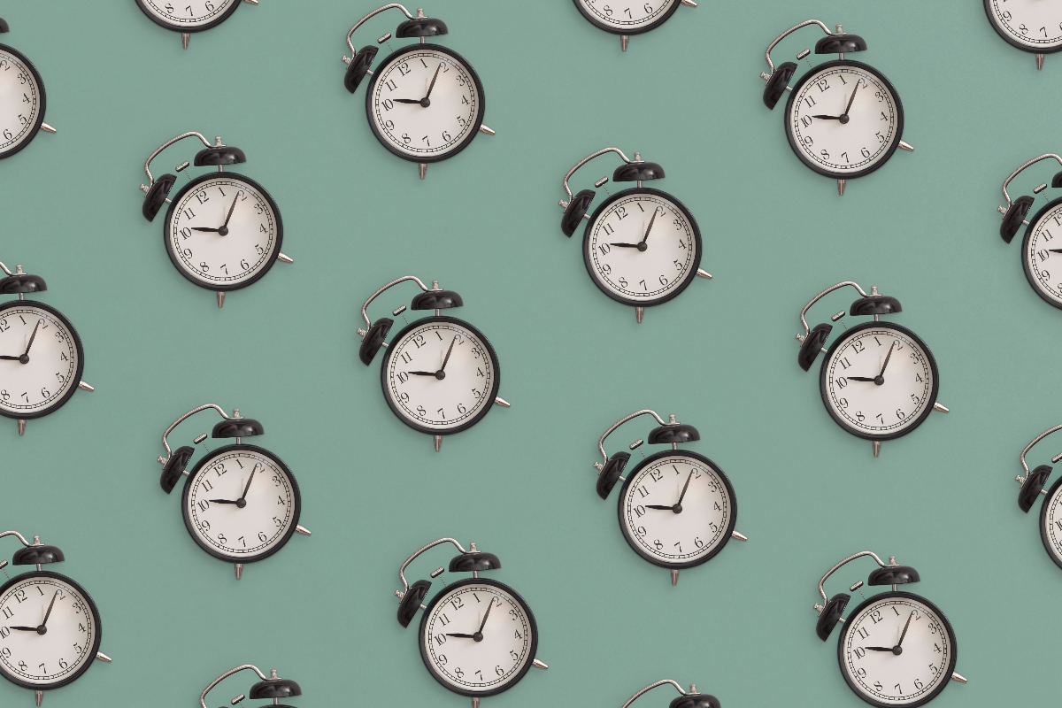 Pattern flat lay composition of black antique alarm clock on green background to illustrate the finding that late morning cardiac surgery is linked to higher cardiovascular mortality