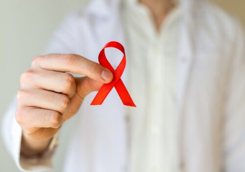 A healthcare professional holding an HIV awareness ribbon