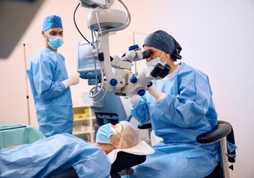 A healthcare professional using a microscope while performing eye surgeryto illustrate uveal melanoma and encouraging registrations for an expert webinar about the disease