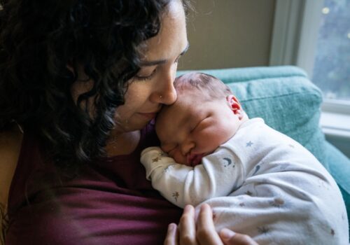 A mother cuddling her newborn baby at home to illustrate that home antibiotic treatment is possible due to updated neonatal infection guidance from NICE