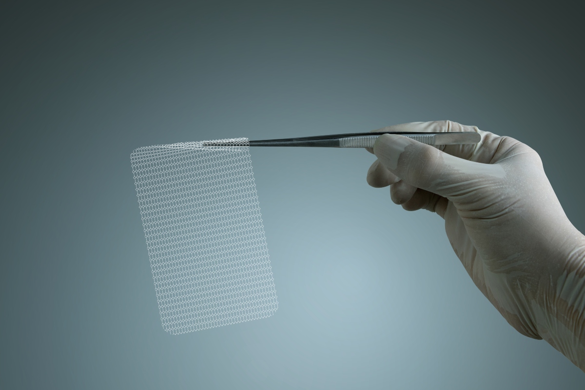 A white-gloved hand holding a piece of surgical mesh in a pair of metal tweezers against a blue-green background to illustrate mesh placement being linked to recurrence and bowel obstruction risk after ventral hernia repair