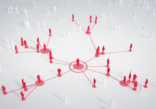 A 3D illustration of red human figures connected by lines in a multi-hub-and-spoke network across a white background, with additional unconnected white figures nearby, representing the spread of infection and the need for AMS and IPC practices, as described at ESCMID Global 2026